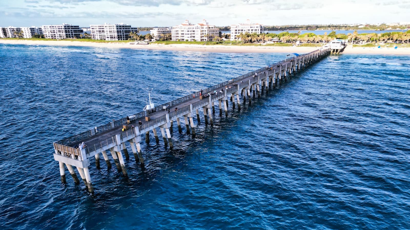 Fishing pier stretching into the Atlantic off a tan Palm Beach County beach.