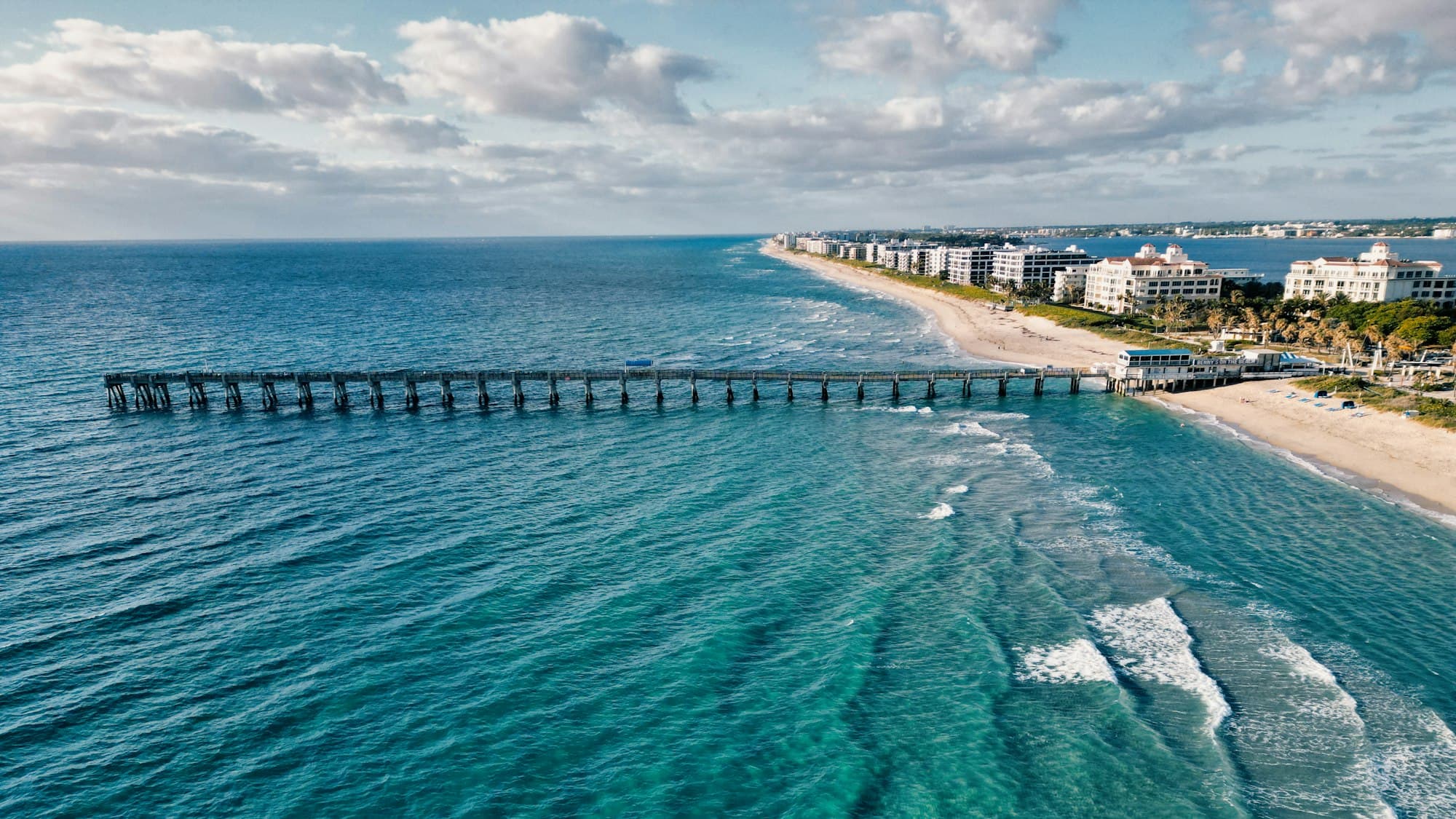 Aerial view of a Palm Beach County Atlantic beach and fishing pier in bright daylight.